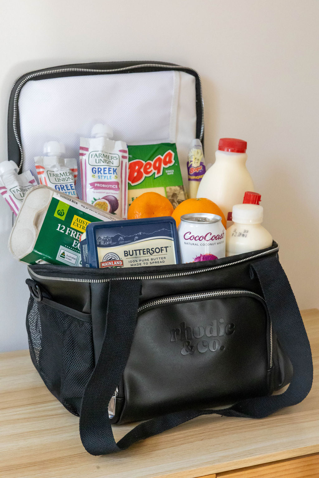 Black cooler bag filled with groceries on a wooden surface