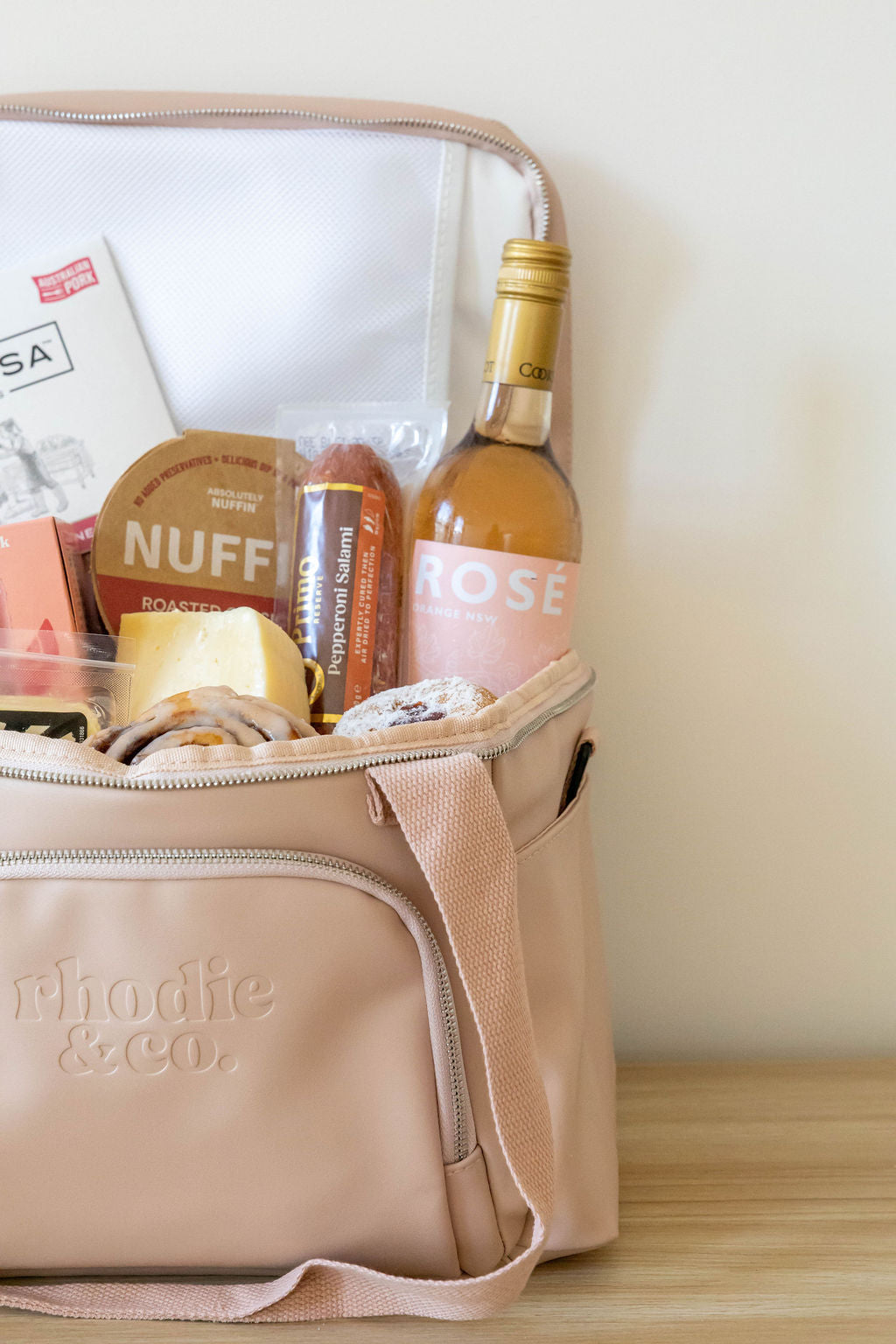Beige thermoelectric bag with snacks and a bottle of wine on a wooden surface